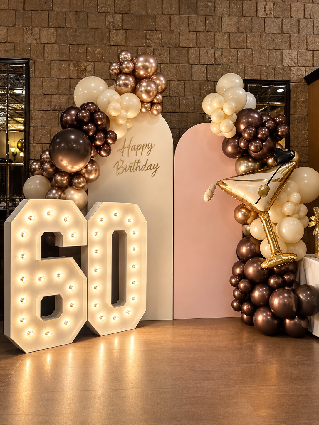 Sixtieth birthday installation with illuminated 60 marquee numbers, bronze and champagne balloons and custom arch backdrops
